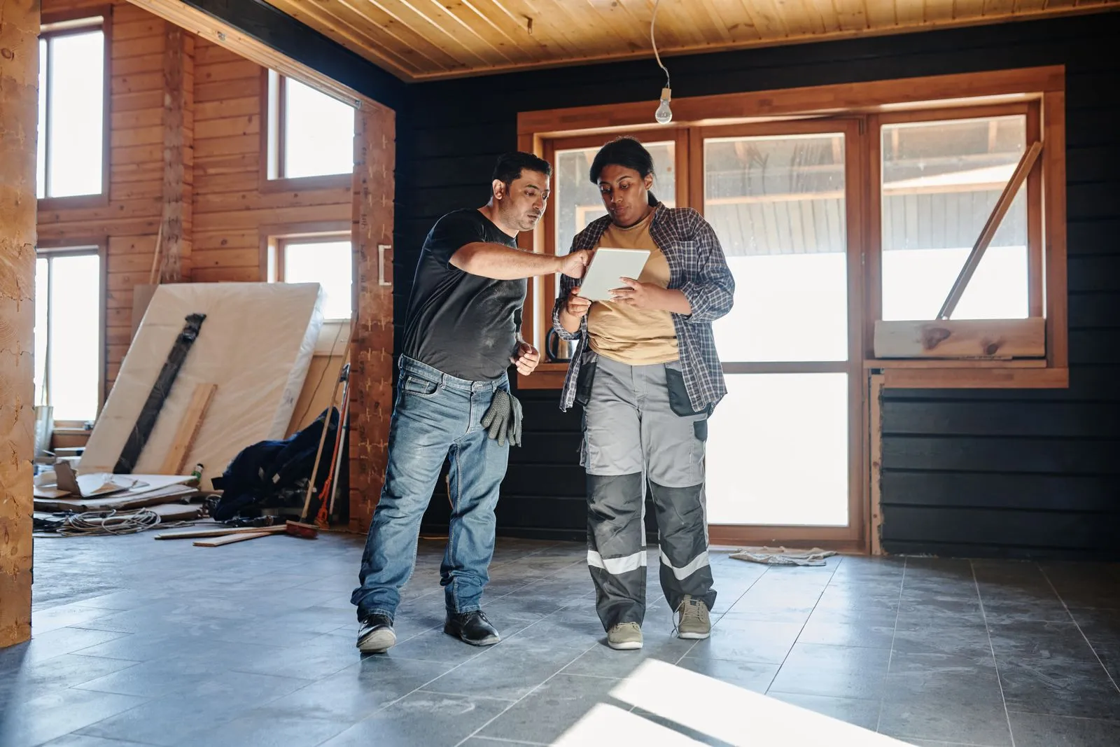 Deux artisans examinent les plans sur une tablette dans une maison en rénovation